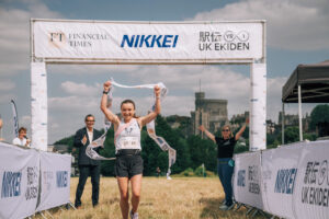Runner crosses the finish line under a gantry featuring the UK Ekiden logo